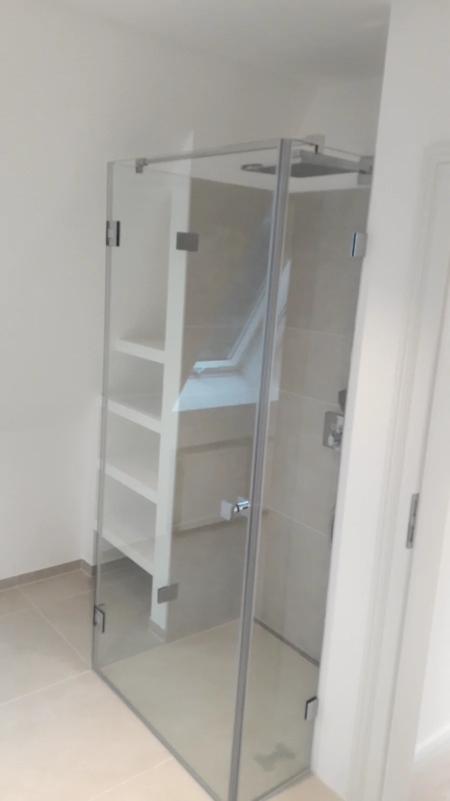 Glasdusche neben dem Handtuchheizkörper Glasdusche mit Metallbeschlägen neben einem weißen Handtuchheizkörper.